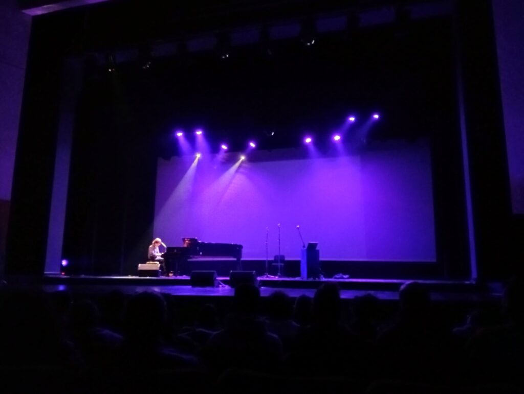 Man playing piano on dimly lit stage