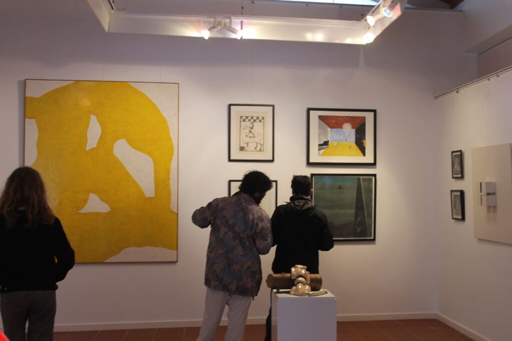 Three people in art gallery looking at paintings