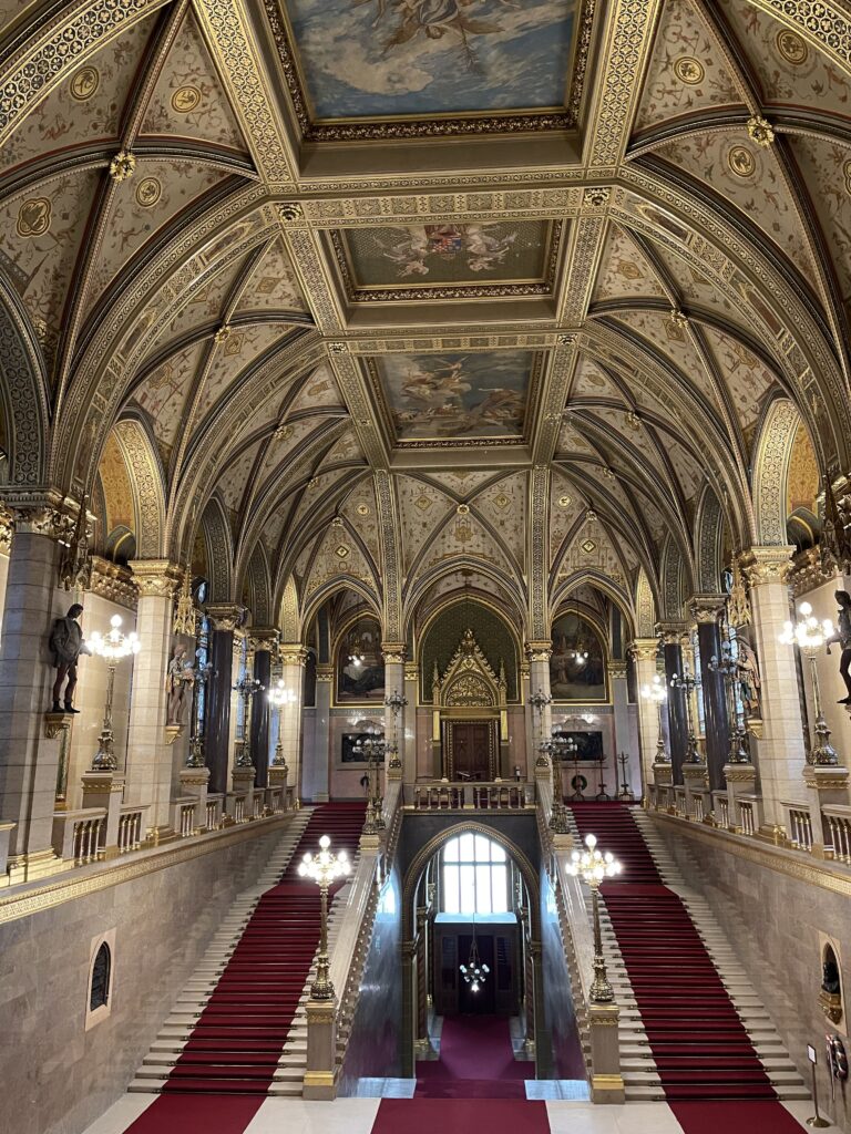 Vast hall with two staircases leading up to second floor with red carpets lining them