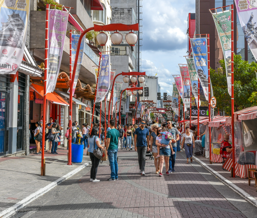 People walking on a pedestrian street with red and white decorations and lamp posts