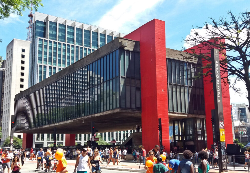 Modernist structure of glass and red concrete holding it above the ground