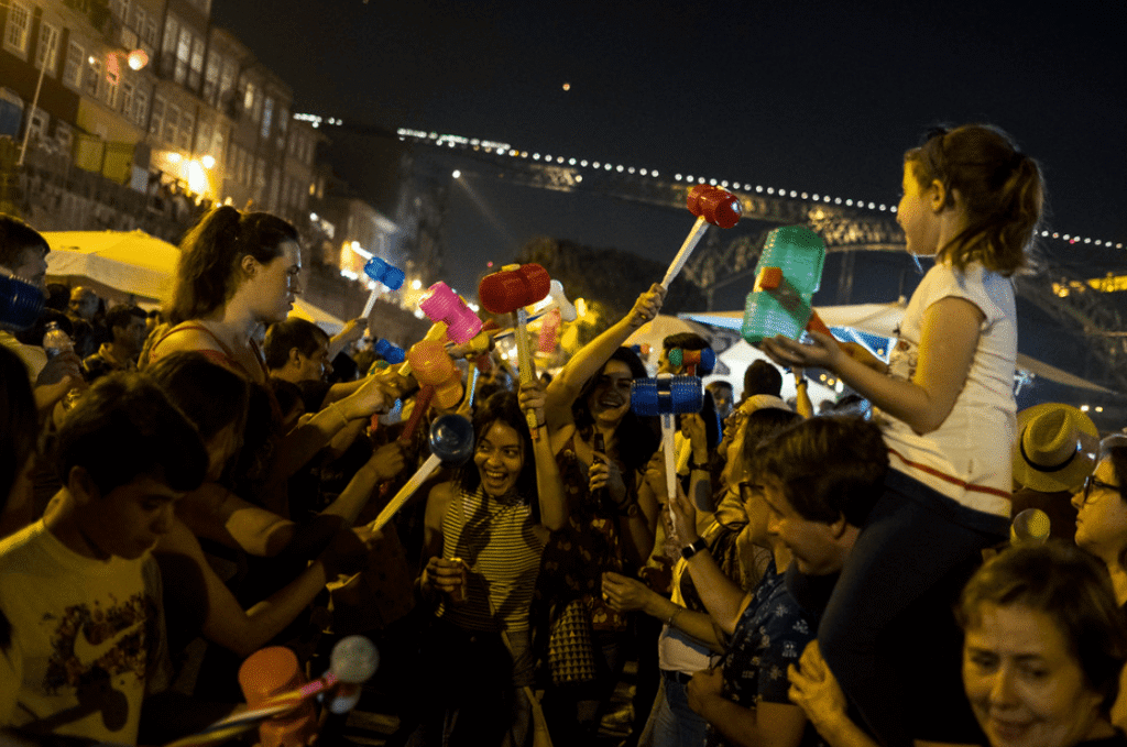 Crowd of people at evening festival playing with plastic hammers