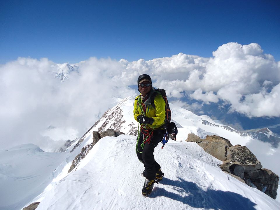 Man standing on summit of snow covered peak