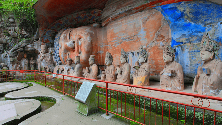 Buddha lying on the side with other statues from rock carvings lines up before him