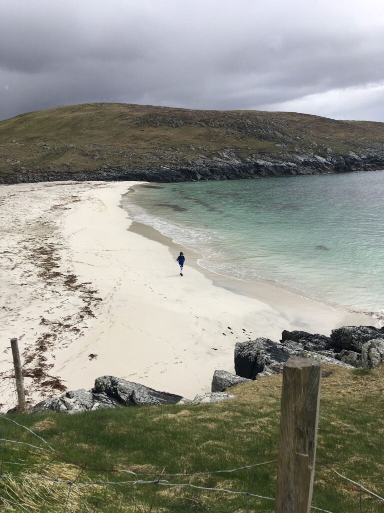 A person on an empty beach inbetween rocks