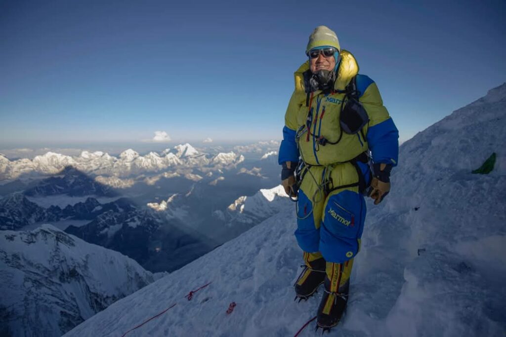 Man standing on side of snow covered peak