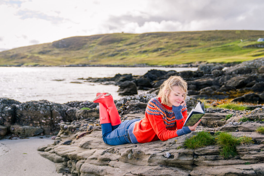 Woman reading a book on cliffs by the water