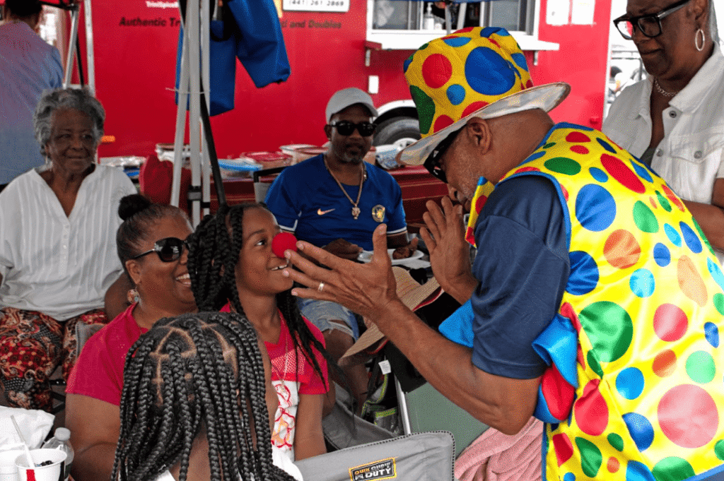 Man in colourful outfit giving red nose to a girl