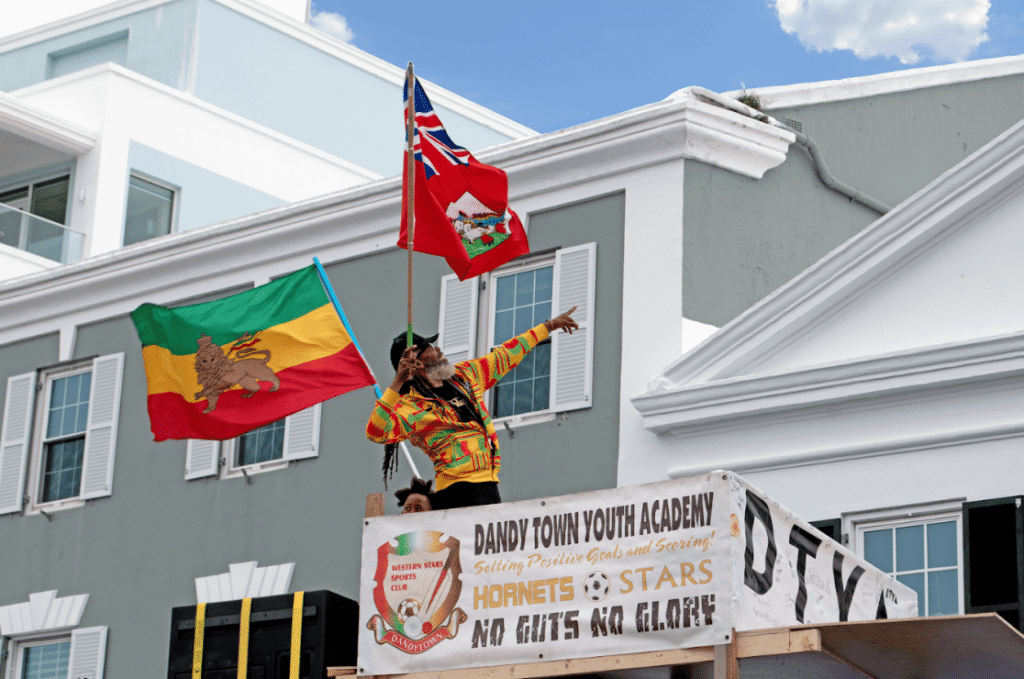 Man holding two flags pointing upwards on a balcony