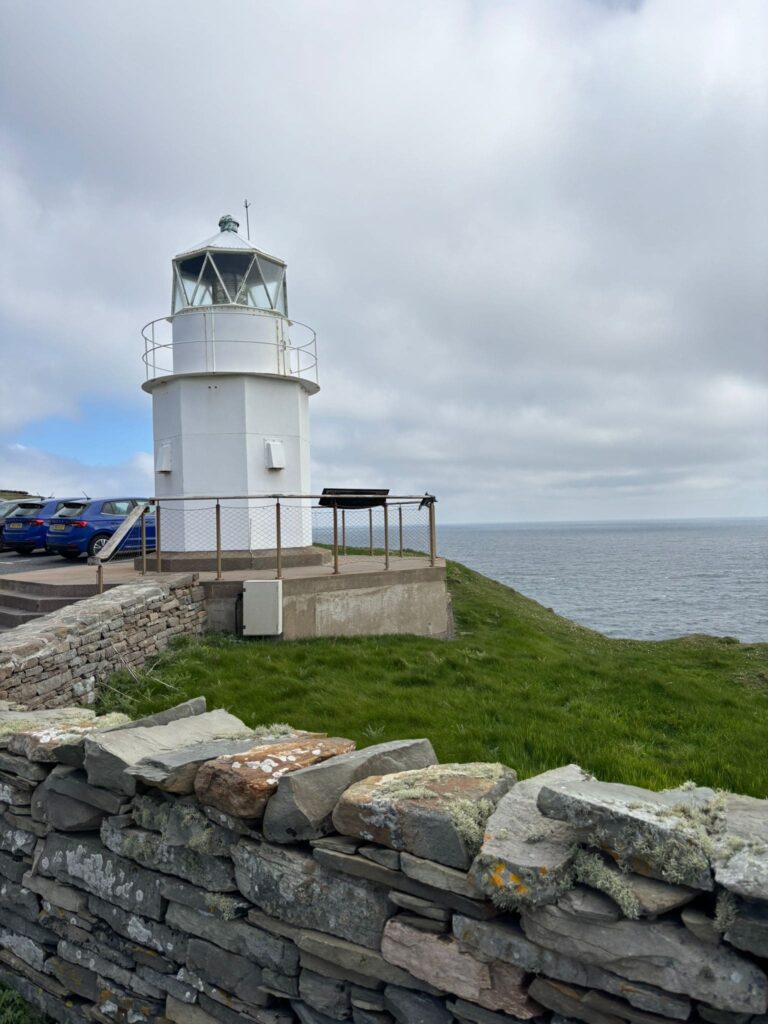 A small white lighthouse on a grassy hill