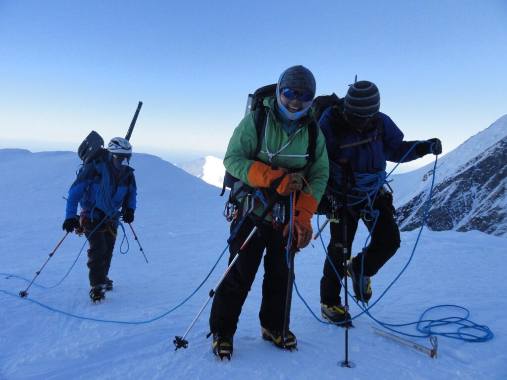 Three climbers getting their rope ready at snow covered spot