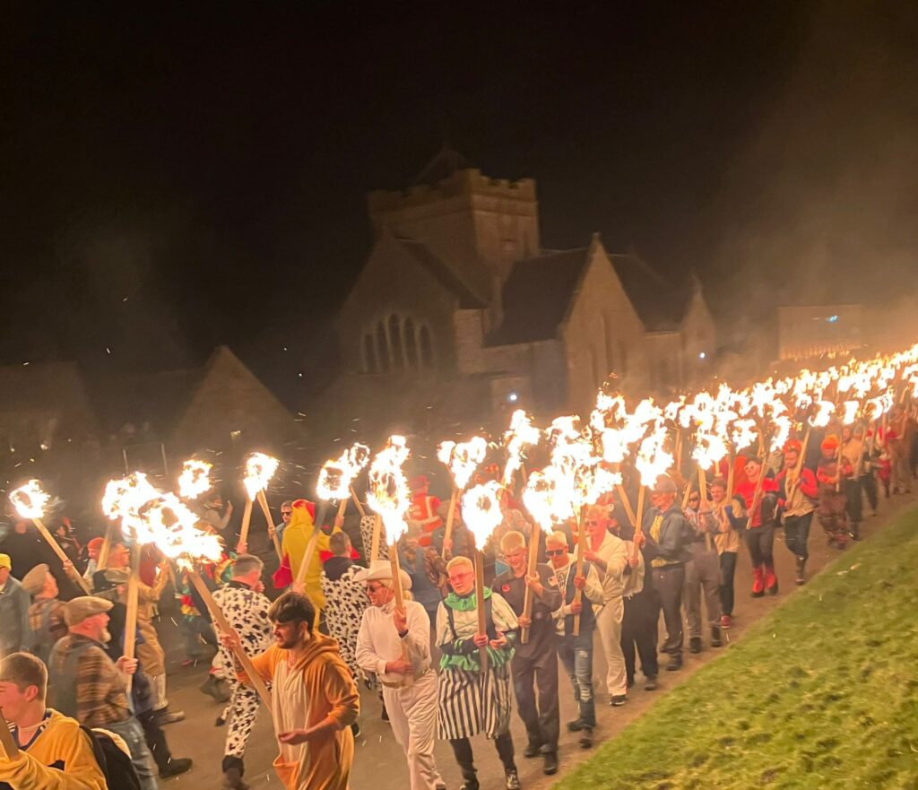 Procession of people holding torches marching near buildings