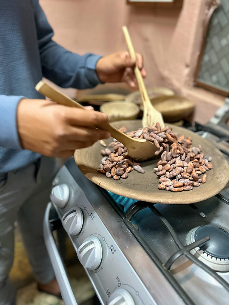 Person mixing and roasting chocolate beans on a stove