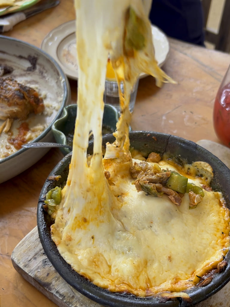 Melting cheese being pulled upwards from a dish