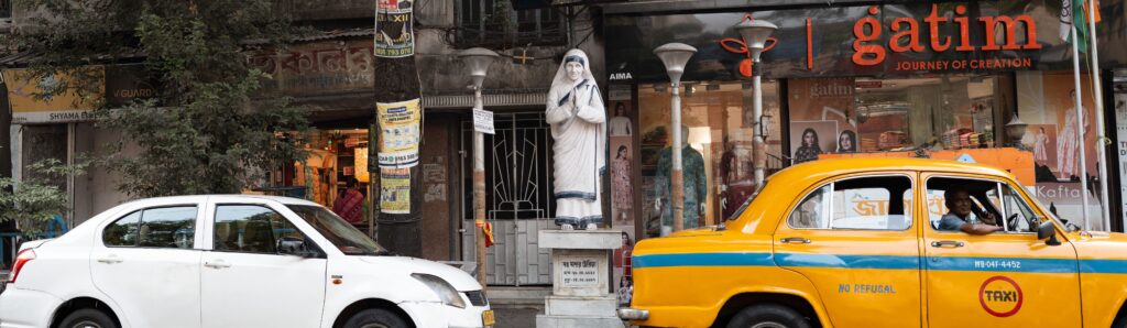 Statue of Mother Teresa between two cars