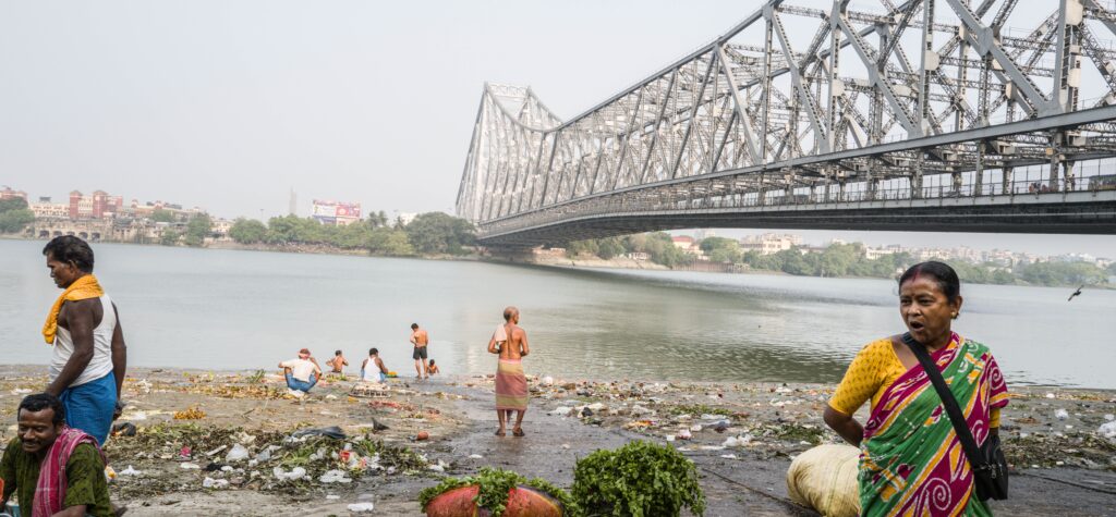 Group of people bathing at a river near a bridge