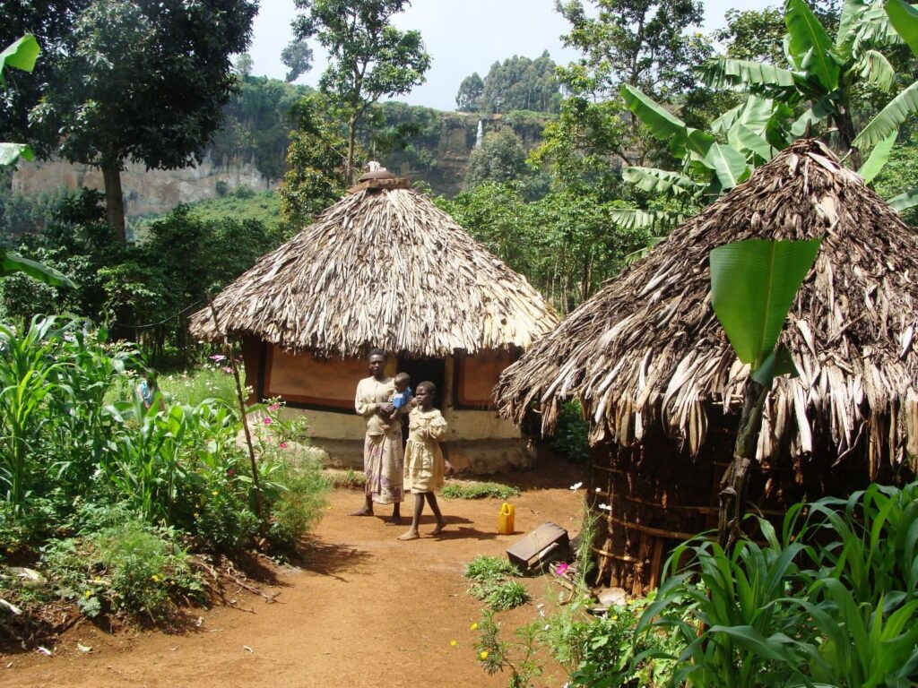 Family outside a thatched roof hut in jungle setting