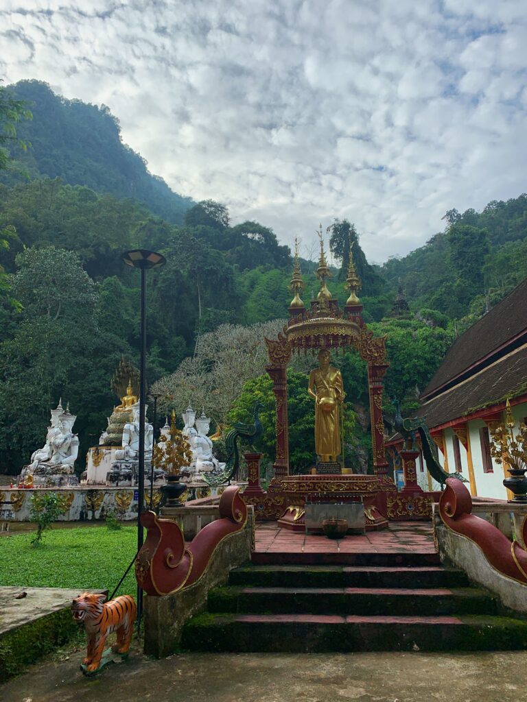 Outdoor temple area with mountain and forest background