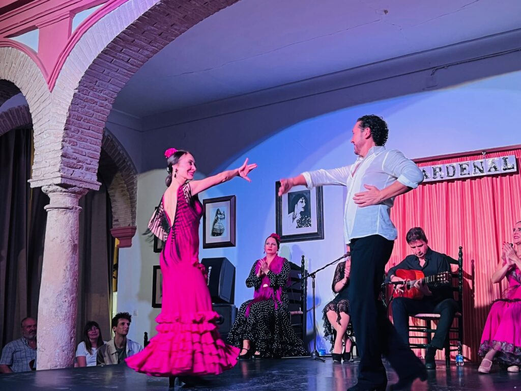 Man and woman on stage performing in flamenco show with guitar player in the back