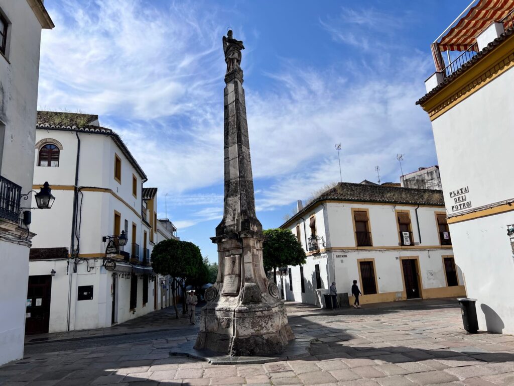 Statue in intersection of cobblestone streets with white-washed buildings on all sides