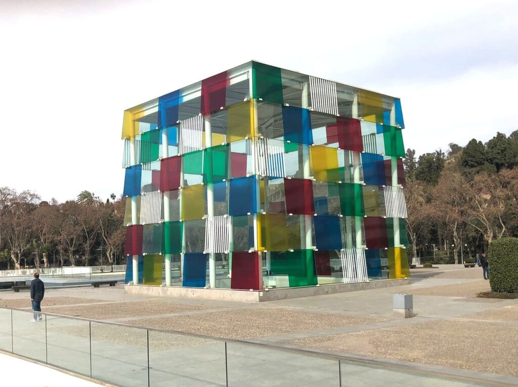 A large cube on a square, made up of smaller coloured cubes