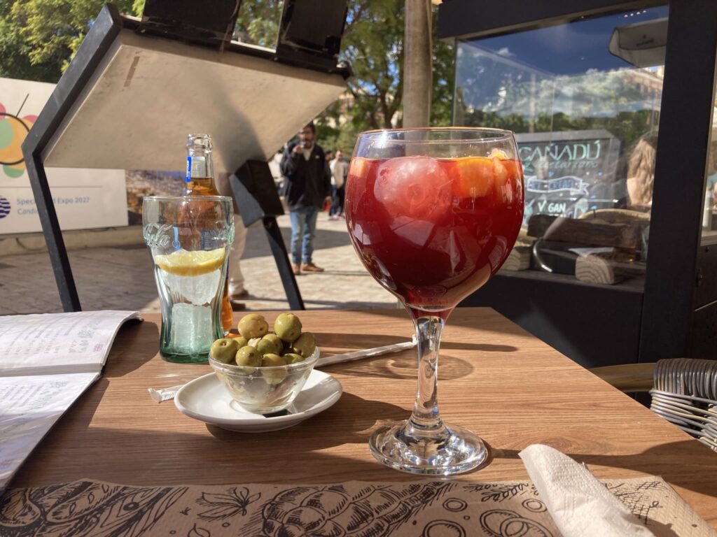 Glass of sangria and small bowl with olives on a table
