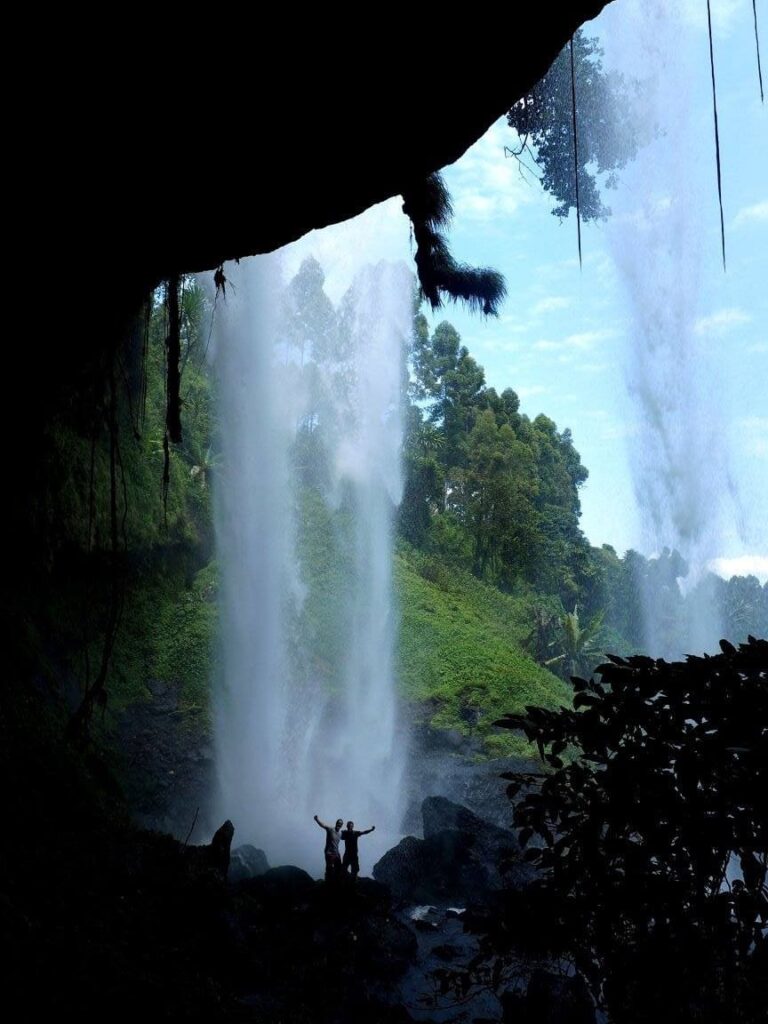 Two men posing under a waterfall