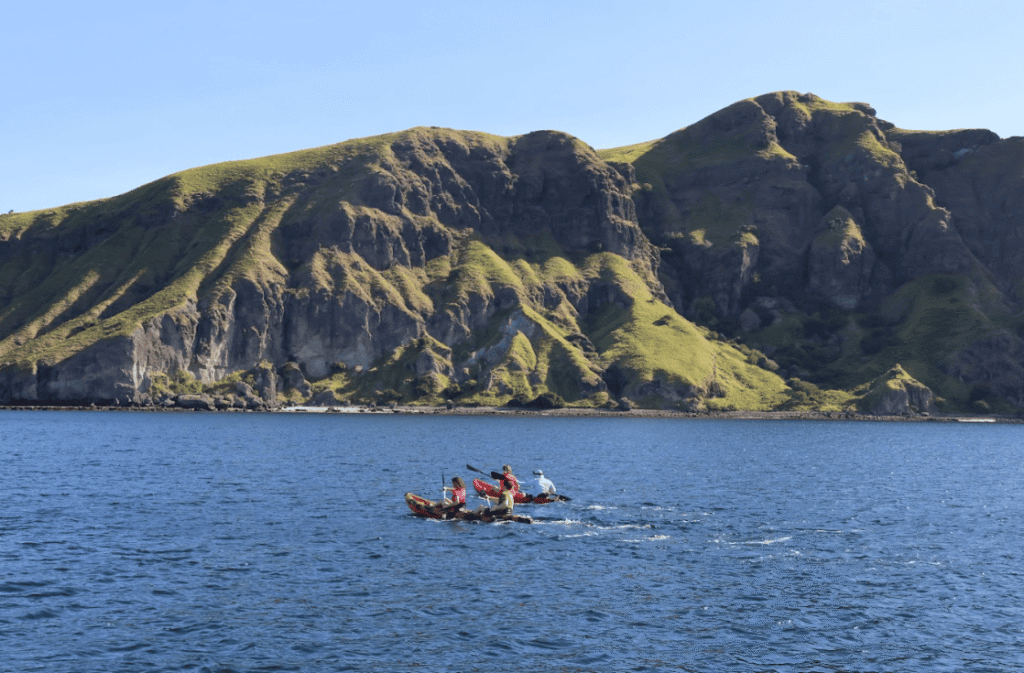 People kayaking near an island with high ridges