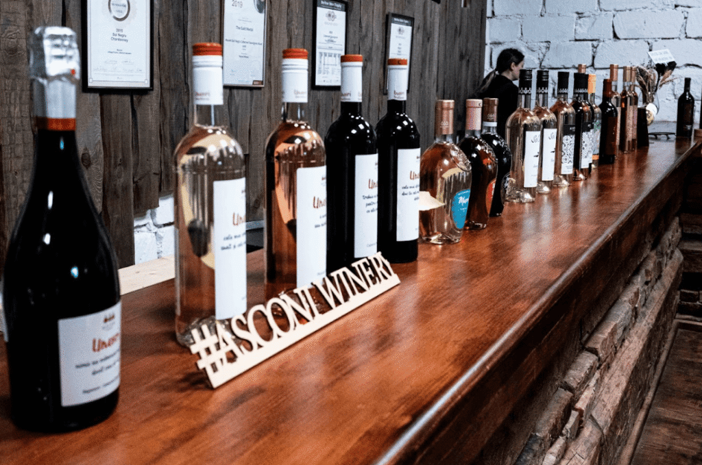 Bar with full wine bottles lined up on it.