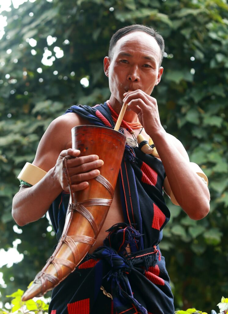 Man in loincloth drinking from a carved horn using a straw