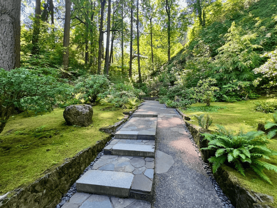 Stoned walkway flanked by manicured lawn and garden