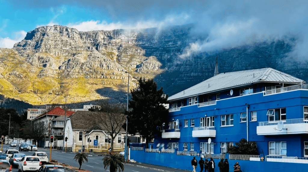 Blue building on a street directly beneath a large mountain