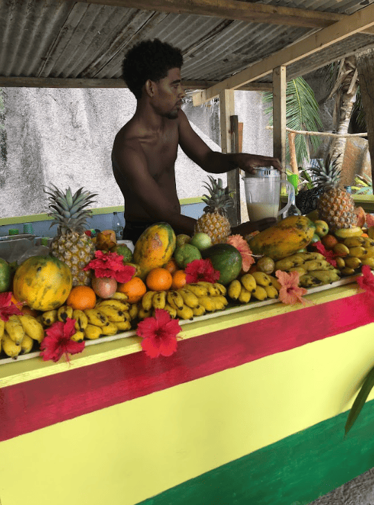 Man blending tropical fruit shakes in stand